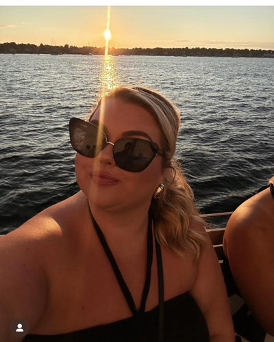 Women on a boat wearing black Sol Kyst cat eye sunglasses while the sun is setting.