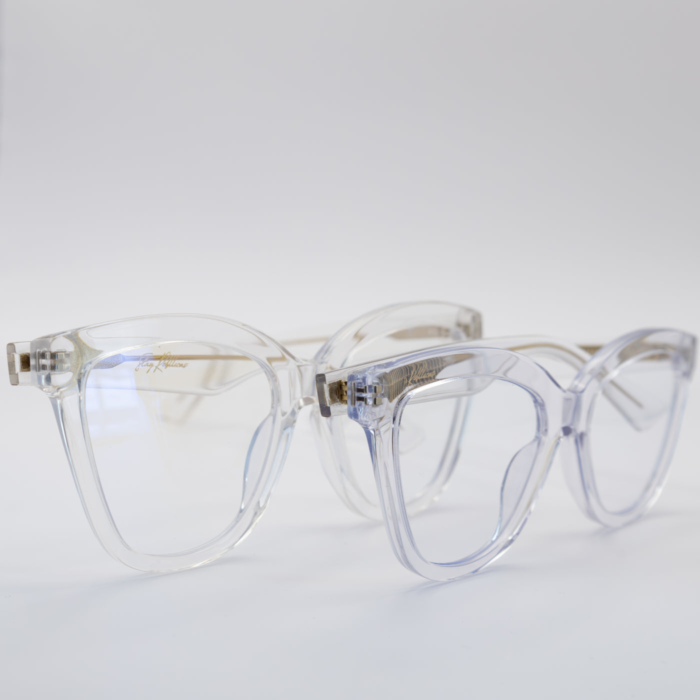 Two pairs of women's blue light glasses with clear lenses and clear frames with gold accents.