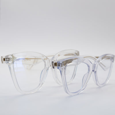 Two pairs of women's blue light glasses with clear lenses and clear frames with gold accents.