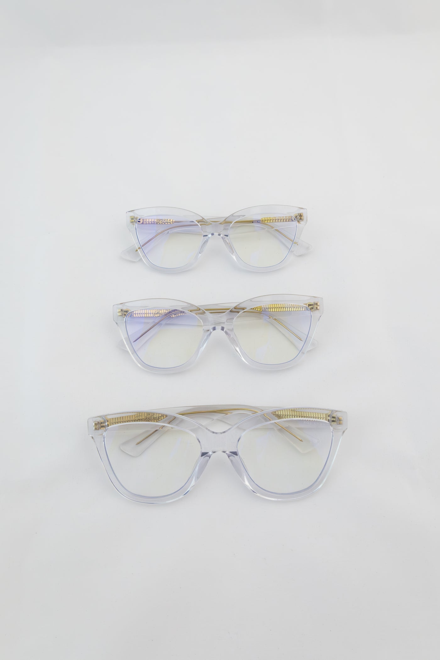 Three women's blue light glasses with clear lenses and clear frames with gold accents.