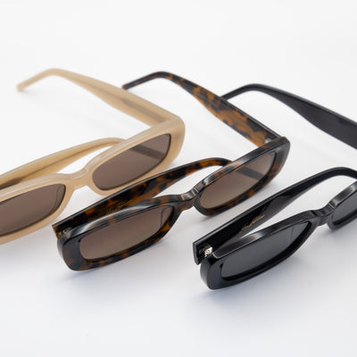 Three rectangular sunglasses in beige, tortoise, and black frames with tinted lenses, displayed in a diagonal arrangement on a white surface.